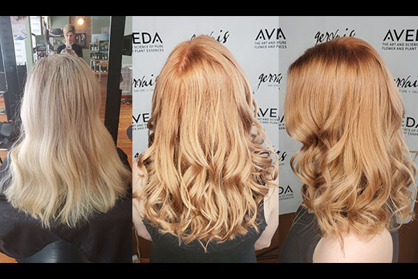 Girl going from Blonde to Red standing in front of Aveda wall
